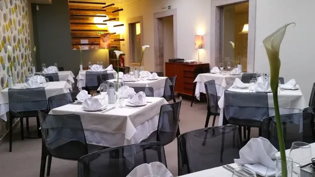 שולחנות ערוכים במפות לבנות ואפורות עם כיסאות שקופים ופרחי קאלה