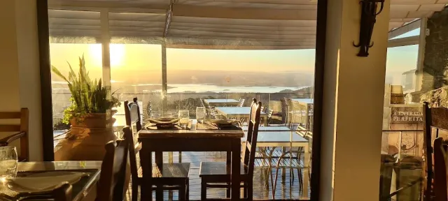 שולחן ערוך ליד חלון גדול אל מישור ואגם באור שקיעה