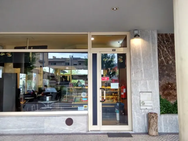 חזית זכוכית של בית קפה שכונתי עם ויטרינה וקירות שיש אפורים