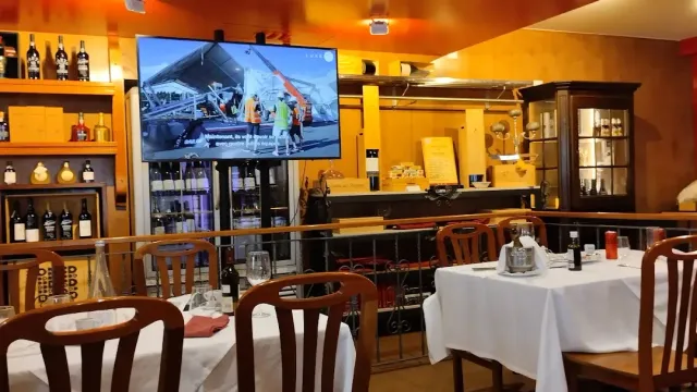 אולם עם חיפוי עץ, מסך גדול על הקיר ושולחנות במפות לבנות