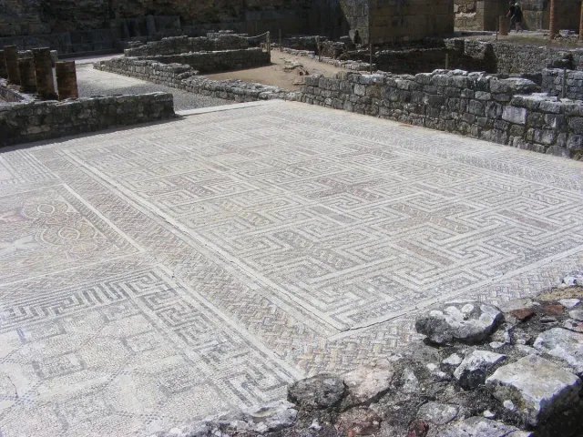 רצפת פסיפס רומית משובצת בדוגמאות גיאומטריות בין חומות אבן