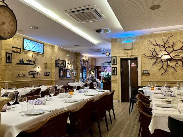 אולם עם קירות אבן בהירים, שעון גדול ושולחנות ארוכים ערוכים