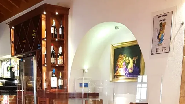 ארון עץ עם בקבוקי יין ותמונת טבע דומם ממוסגרת בגומחה לבנה