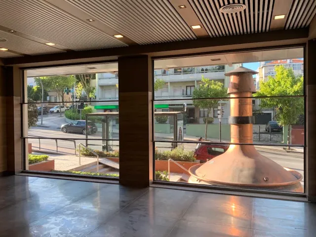 חלל ריק עם תקרת עץ, חלונות רחבים אל הרחוב ומיכל נחושת מבריק