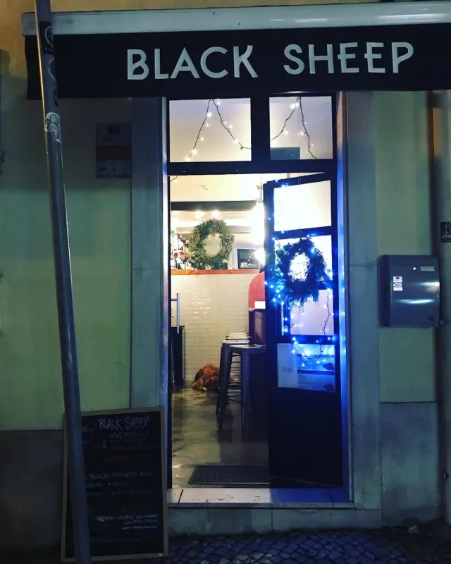חזית קטנה בלילה עם דלת פתוחה, זרי ירק ושרשרות אורות