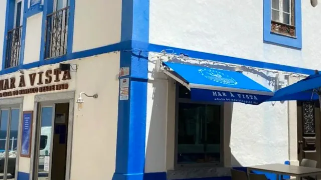 חזית לבנה וכחולה עם סוכך כחול וכתובת מוטבעת על הקיר