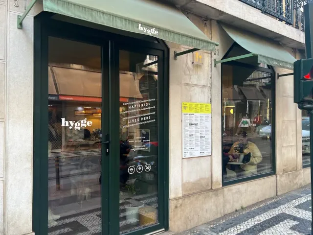 חזית בית קפה עם מסגרות ירוקות, סוככים ולוחות תפריט על הקיר