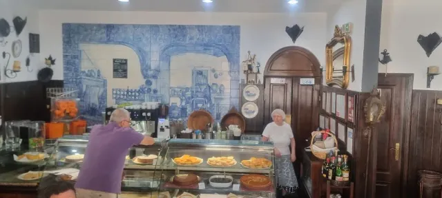 דלפק ויטרינה עם מאפים, קיר אריחים כחולים מצוירים ואנשים מאחורי הדלפק