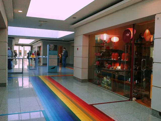 מסדרון קניון קטן עם רצפה בפסי צבע וחלונות ראווה