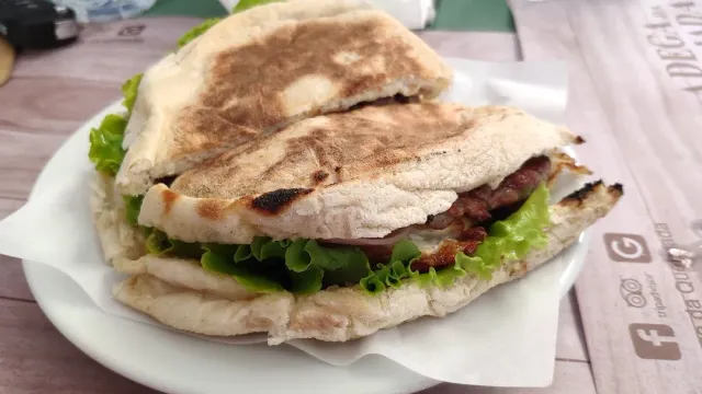 כריך בלחם שטוח קלוי עם נתחי בשר ועלי חסה בצלחת