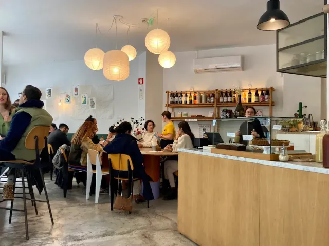 חלל בהיר עם פנסי נייר עגולים, דלפק עץ בהיר וסועדים סביב שולחנות