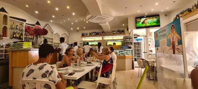 חלל מלא סועדים בשולחנות לבנים מול דלפק פתוח ומדפי בקבוקים