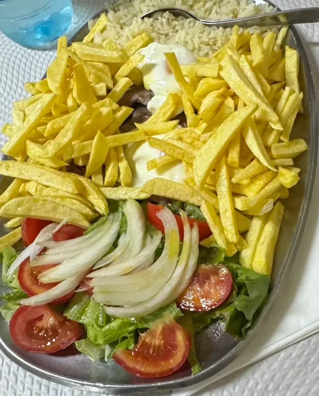 מגש מתכת עם צ׳יפס, אורז, ביצת עין וסלט עגבניות, חסה ובצל