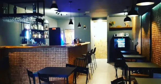 דלפק בר מרוצף עם שרפרפים גבוהים, מנורות תלויות ותאורה כחולה