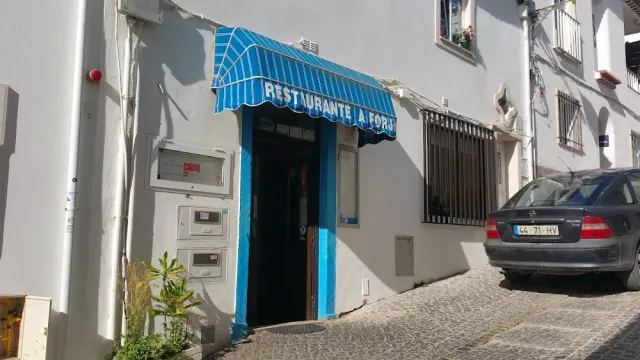 כניסה כחולה עם סוכך פסים ברחוב מרוצף צר, ומכונית חונה לידה